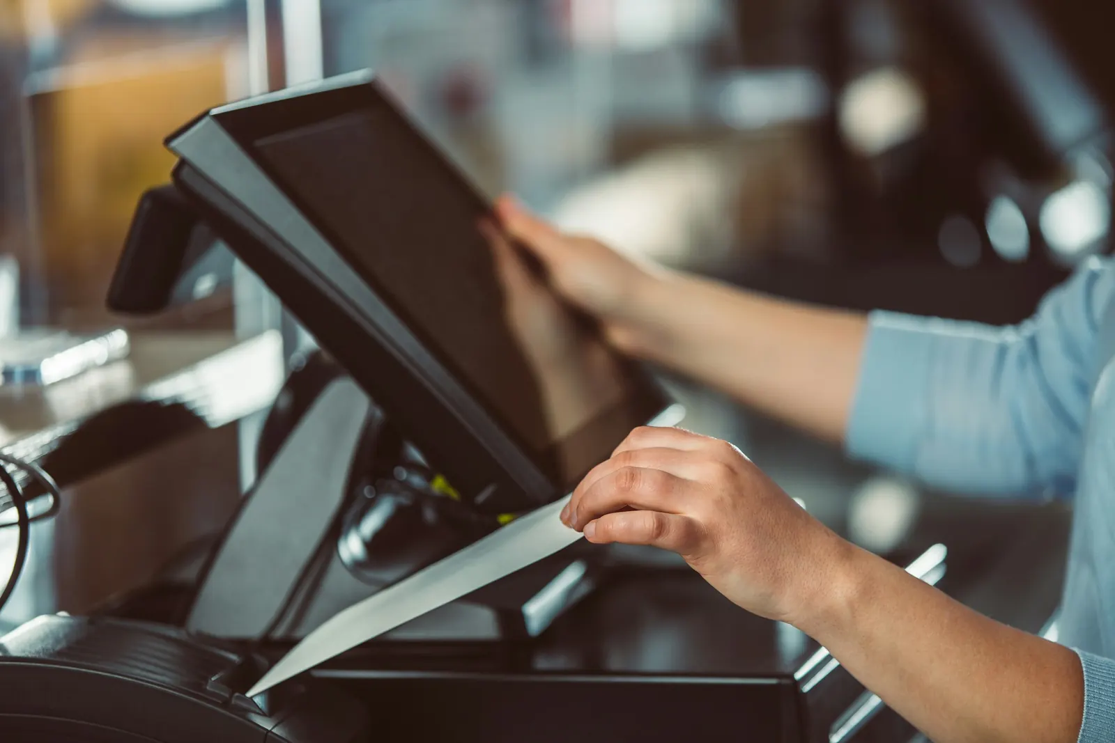 Staff member using a touchscreen point-of-sale system at a restaurant counter